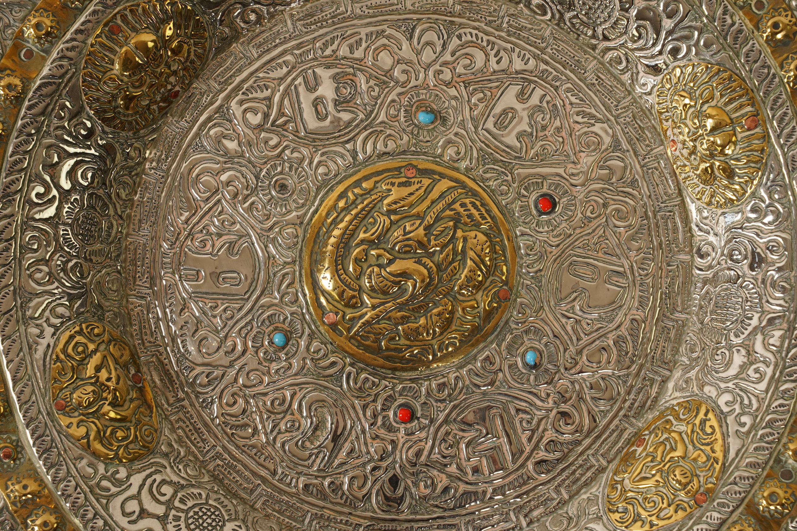 A graduated set of three Nepalese repoussé white metal and brass chargers, first half 20th century